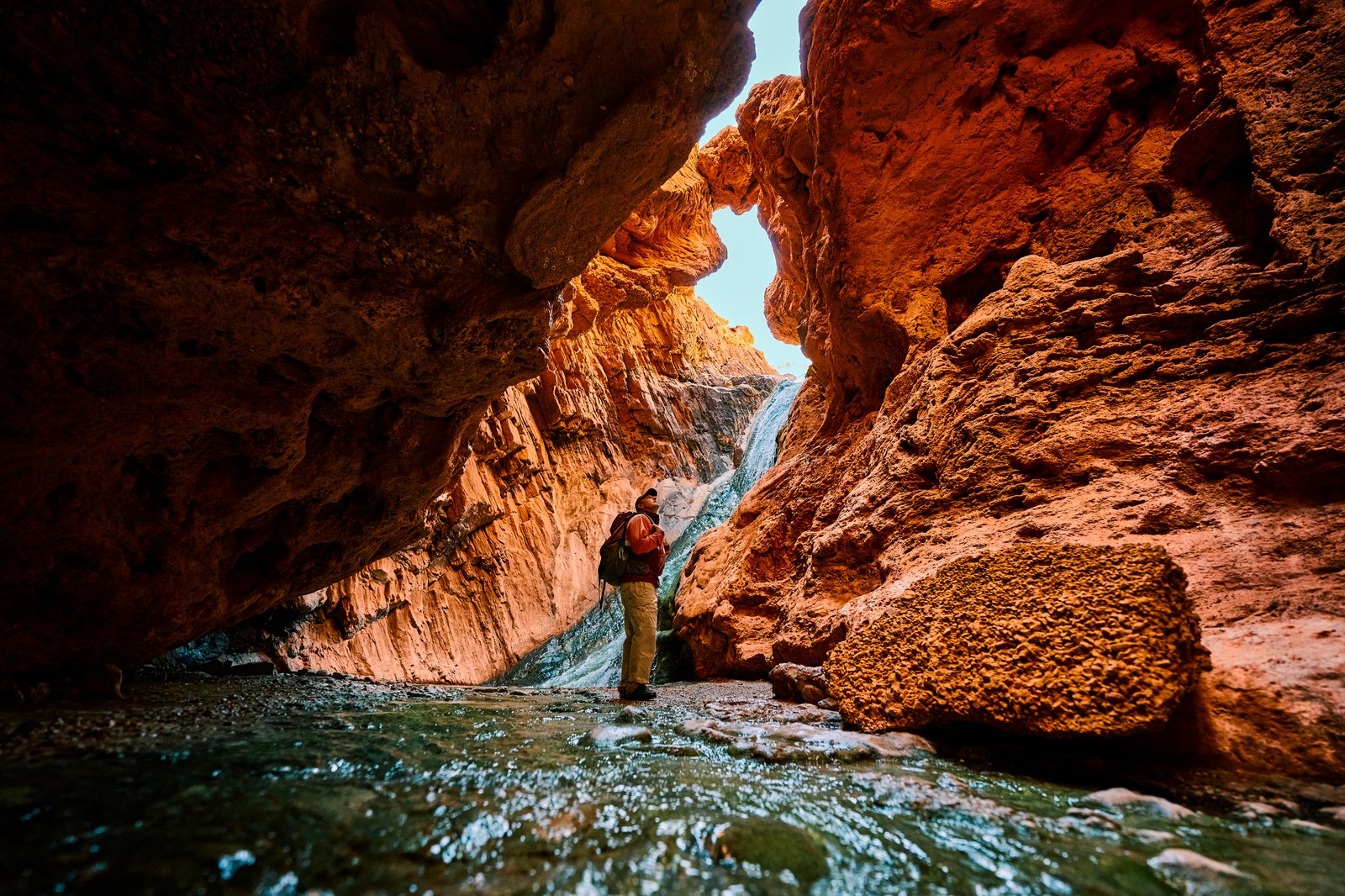 Hiker exploring a copper-hued Arizona grotto